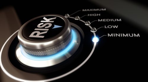 Switch button labeled "risk" positioned on the word minimum, black background and blue light. Conceptual image for illustration of Risk management or assessment.