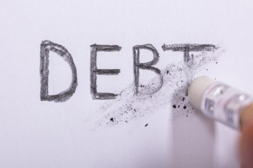 Close-up Of Pencil Eraser Erasing the word Debt in pencil On White Paper